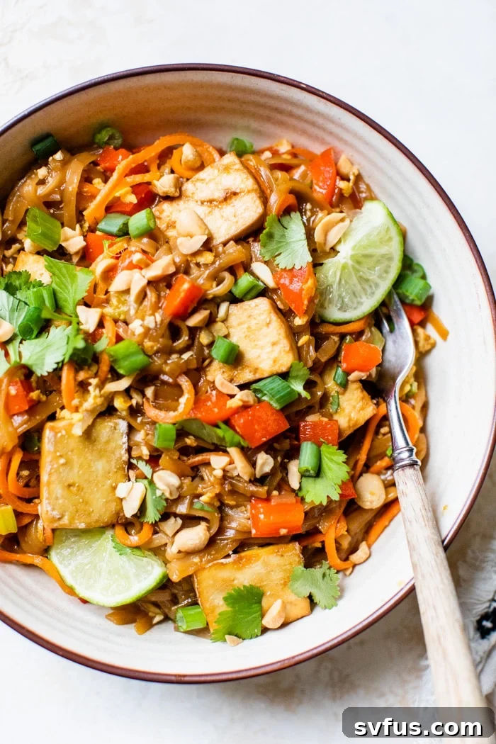 Noodles in a bowl with crispy tofu, green onions, and peanuts