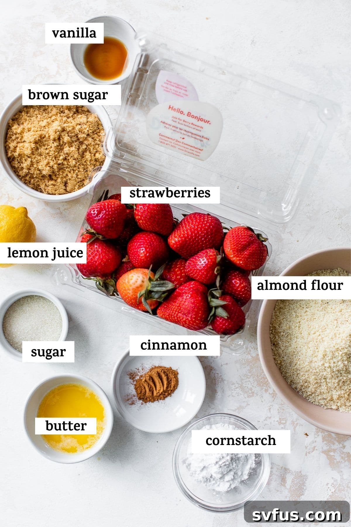 A flat lay photograph showcasing the essential ingredients for making a delicious strawberry crisp, including fresh strawberries, sugars, almond flour, and butter.