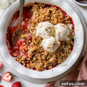 strawberry crisp in a white pie pan topped with three scoops of vanilla ice cream