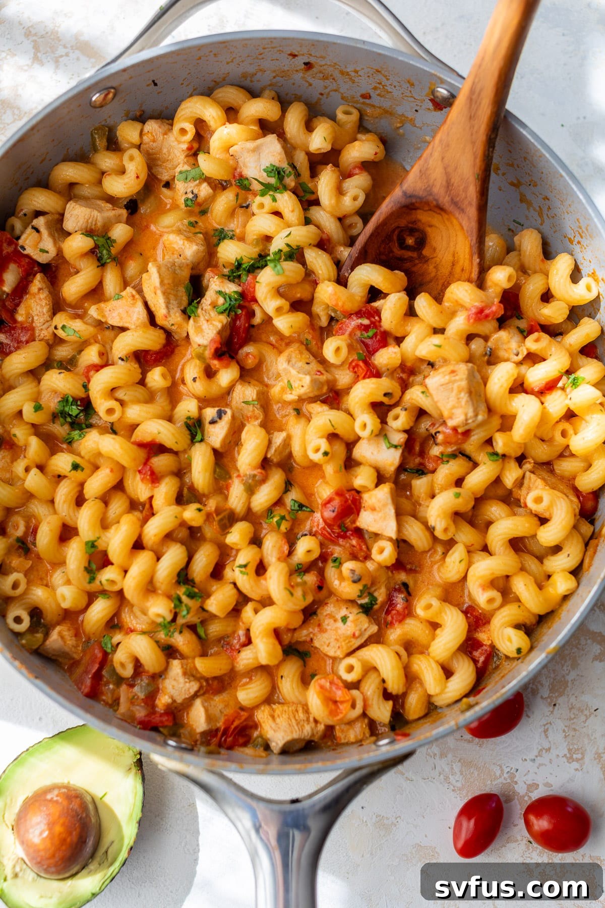 A wooden spoon stirring the rich, creamy Chicken Fajita Pasta in a large skillet, showcasing its appealing texture and vibrant colors.