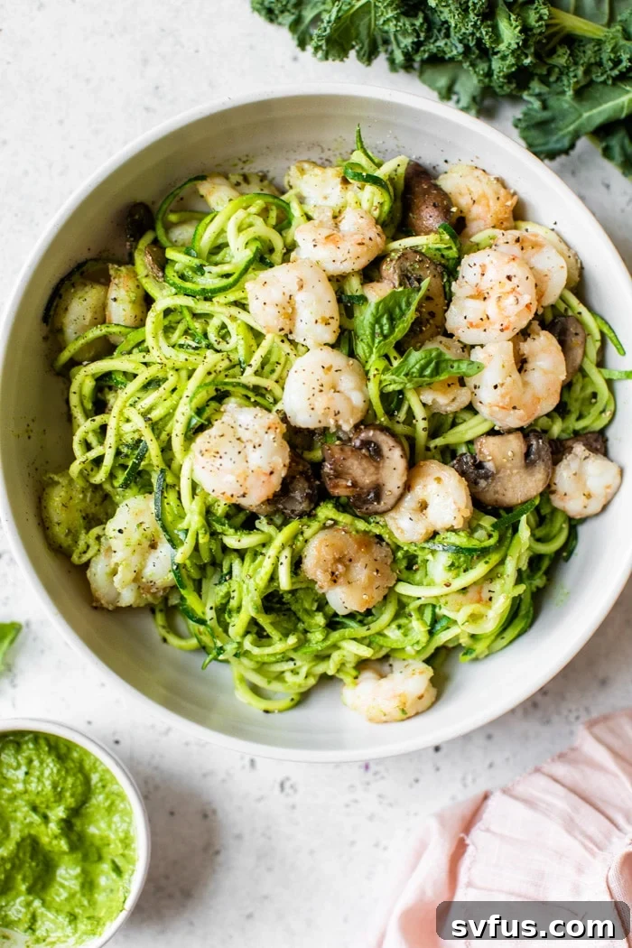 A beautifully plated bowl of Kale Pesto Zoodles topped with pan-seared shrimp and mushrooms, ready to be enjoyed.