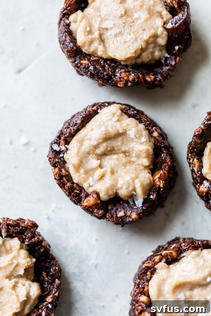 Close-up of a single no-bake chocolate caramel thumbprint cookie on a wooden table.
