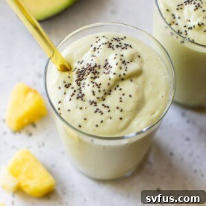 A glass of pineapple avocado smoothie topped with chia seeds, ready to be enjoyed.