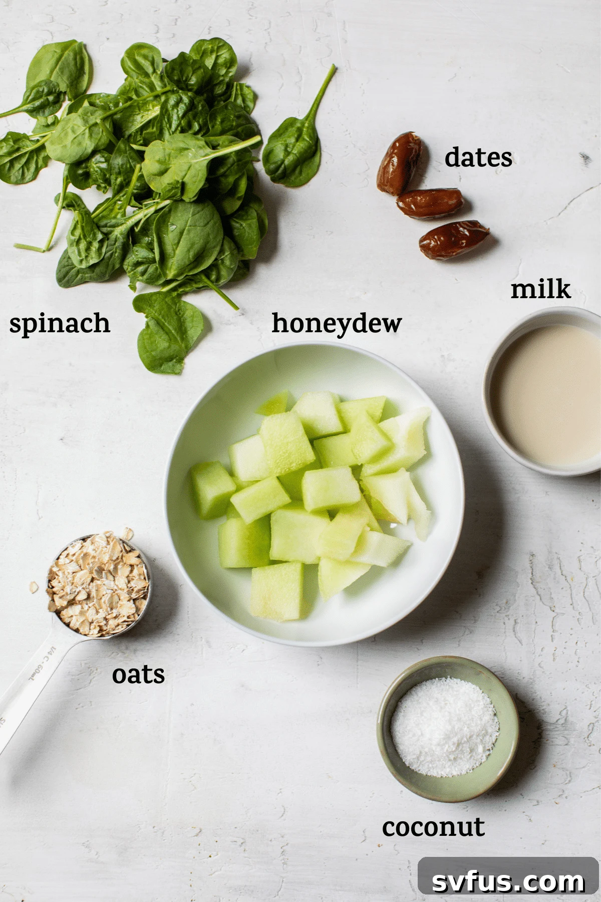 Collection of fresh smoothie ingredients including honeydew cubes, spinach, dates, oats, coconut flakes, and a glass of milk, with text overlay.