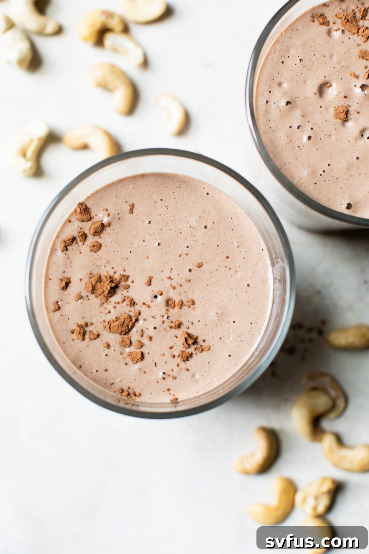 A close-up shot of a healthy chocolate cashew smoothie in a glass, with small bubbles on top, ready to be enjoyed.
