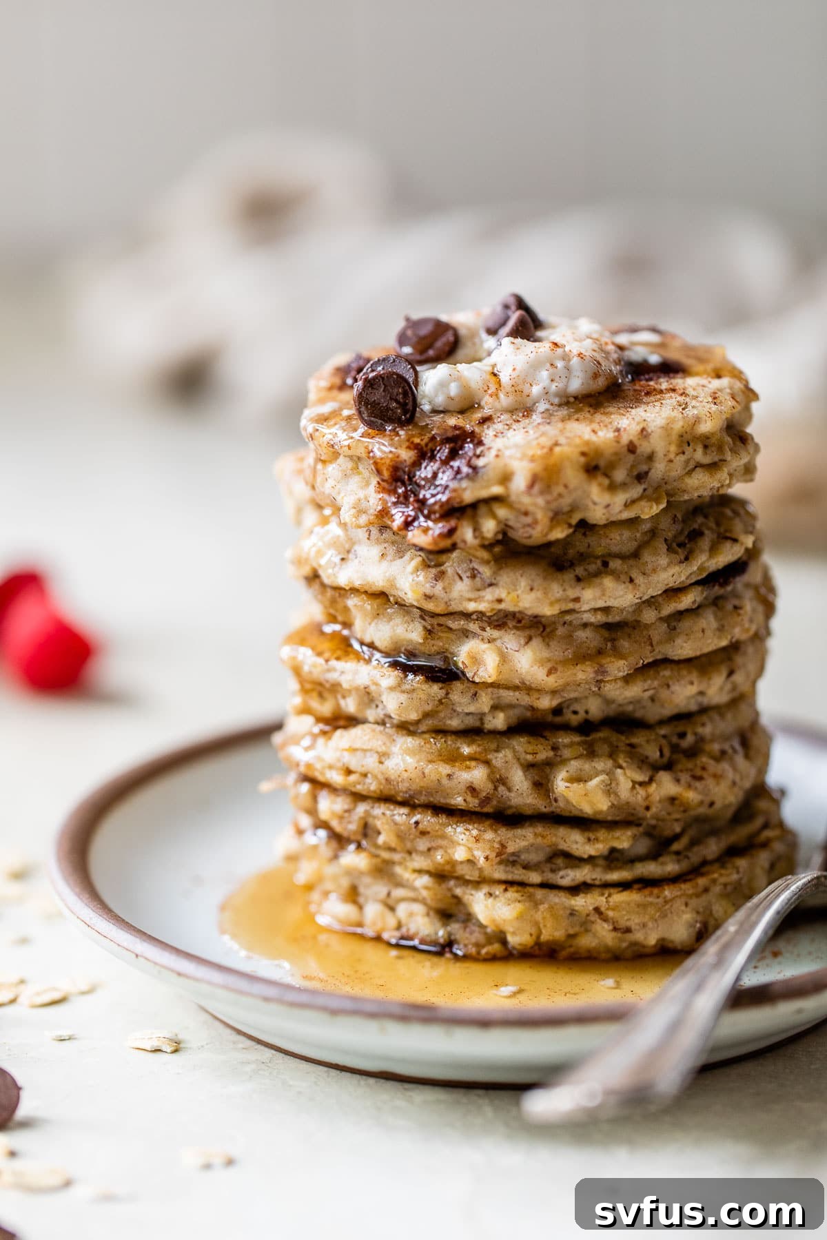 A beautifully stacked plate of golden vegan oatmeal pancakes, drizzled with rich maple syrup and ready to be enjoyed.