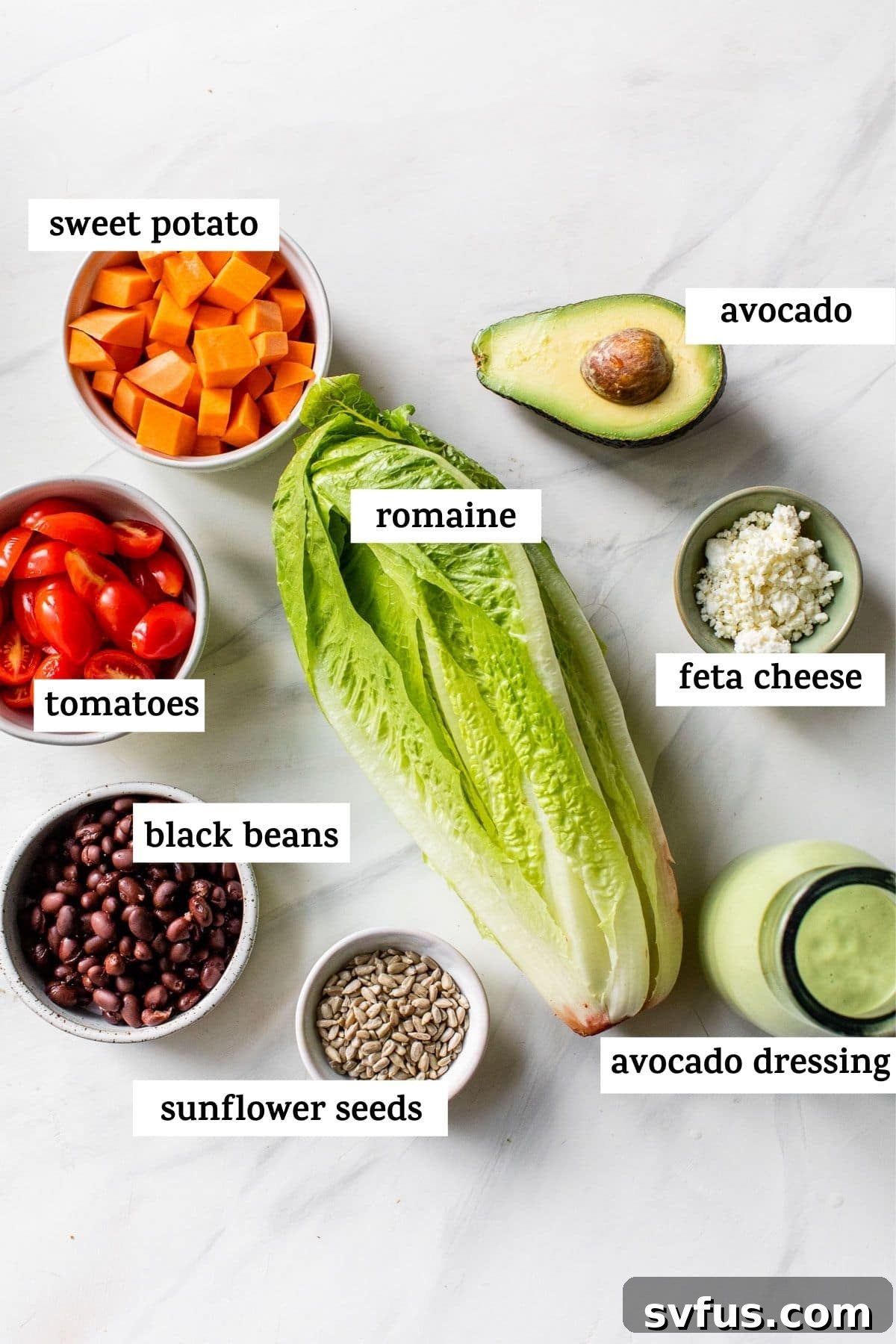 A flat lay photograph showcasing all the fresh ingredients needed to make the sweet potato salad, including sweet potatoes, lettuce, tomatoes, and avocado.