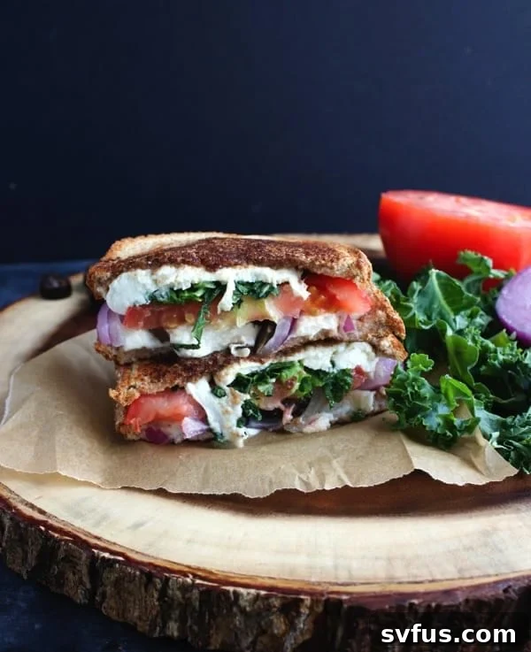 Close-up of a perfectly grilled Mediterranean sandwich, showing the melted cheese and vibrant vegetable fillings.