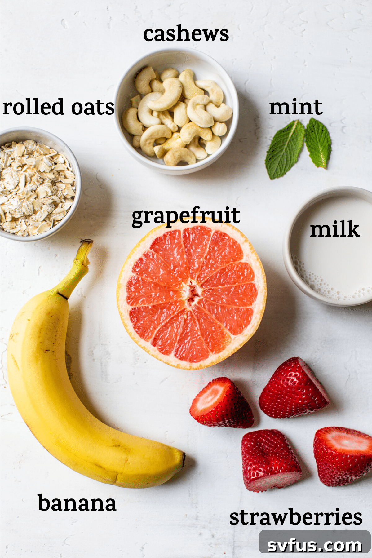 All the ingredients for a grapefruit smoothie laid out on a table, including grapefruit, strawberries, oats, cashews, and mint leaves, with text overlay.