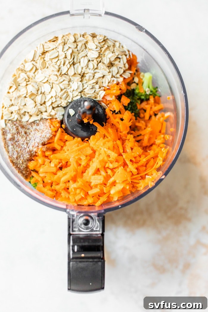 Close-up of carrots, oats, and broccoli in a food processor, ready to be blended for the burger mixture