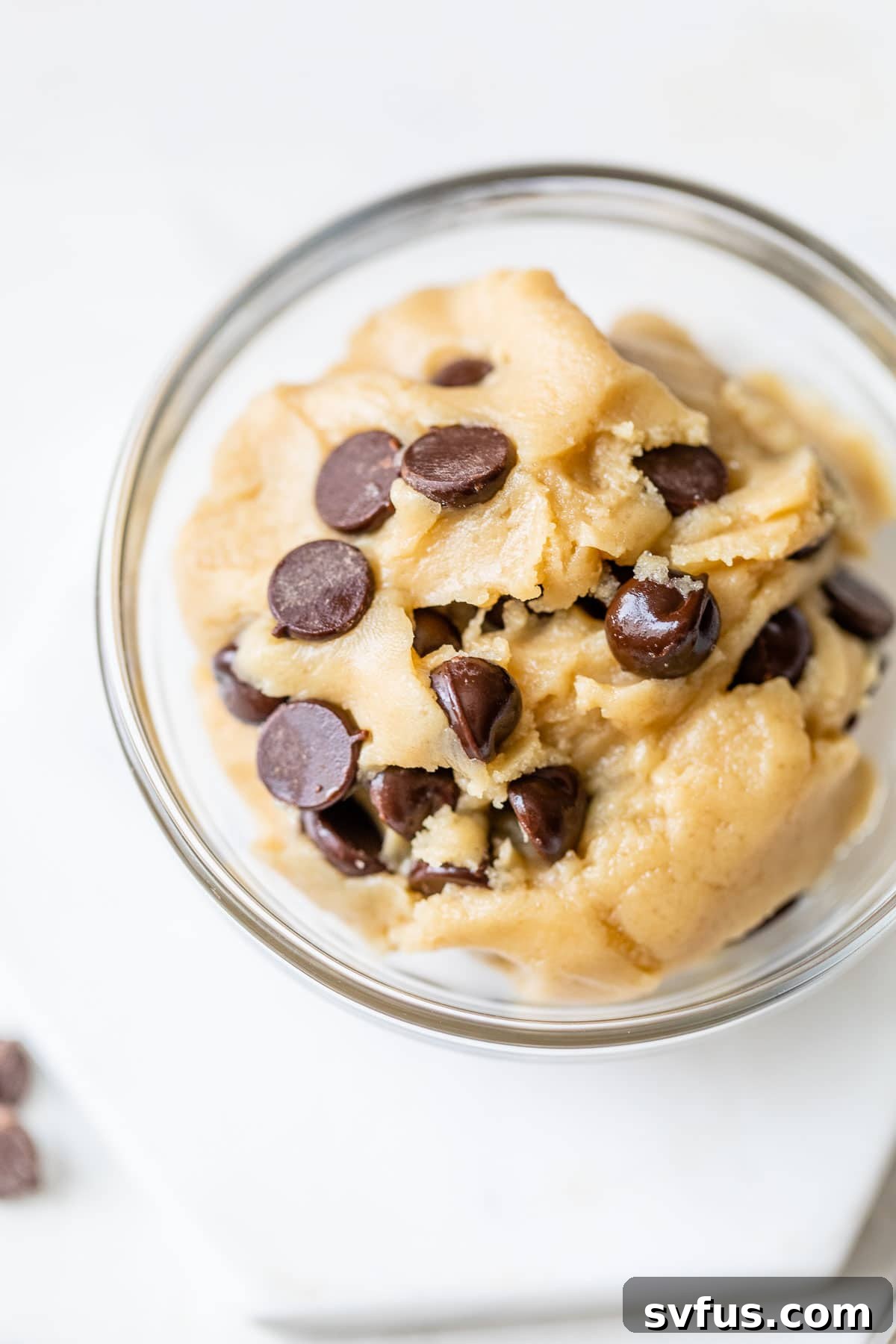 A small glass bowl filled with rich, chocolate chip edible vegan cookie dough, showcasing its perfect texture and inviting appearance.