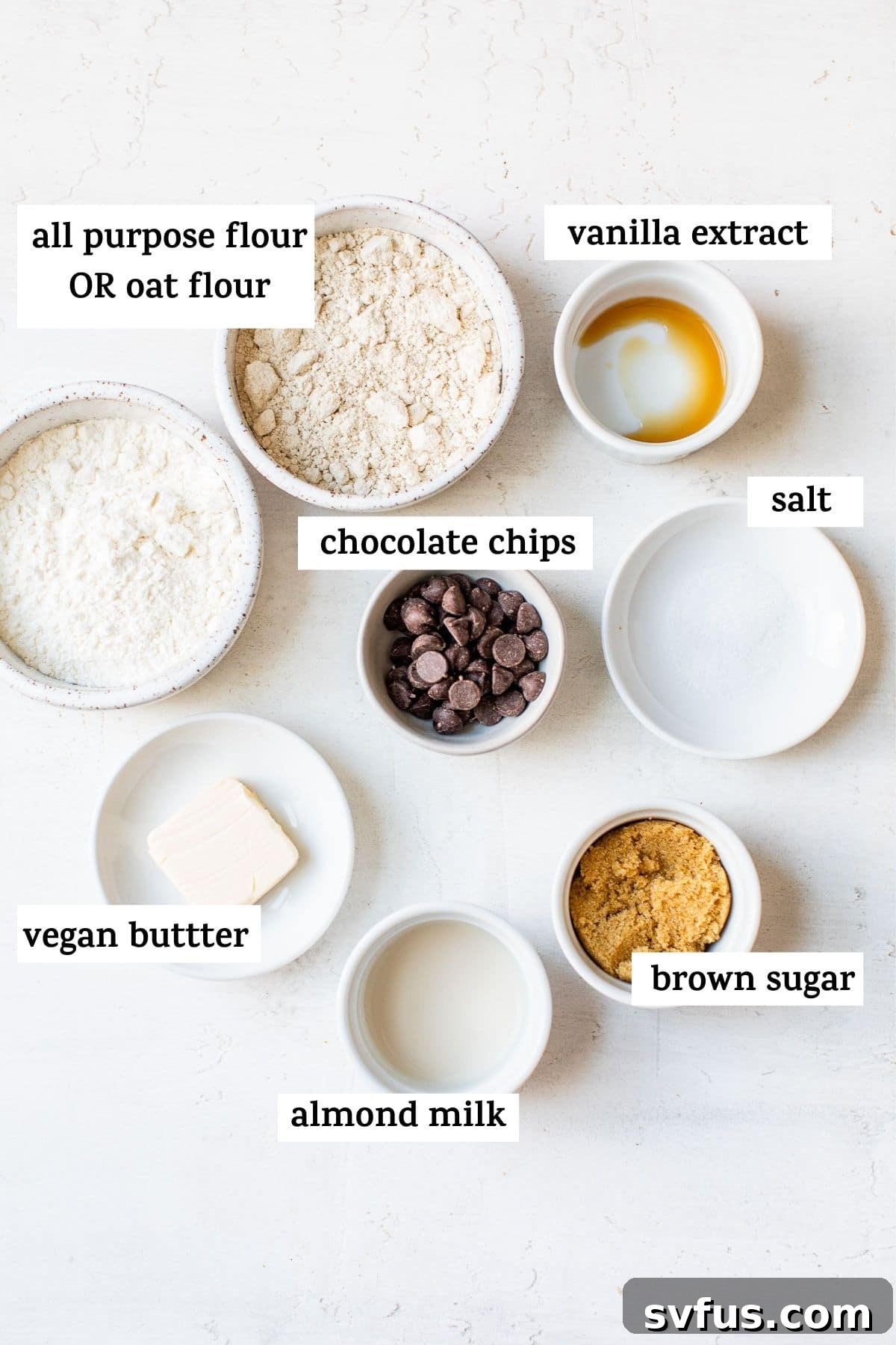 A collection of essential ingredients for vegan cookie dough, including a bowl of flour, brown sugar, a block of dairy-free butter, and a scattering of vegan chocolate chips, arranged aesthetically on a kitchen counter.