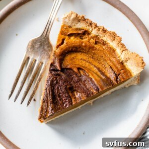A perfectly baked slice of Paleo Chocolate Pumpkin Pie on a plate with a fork.