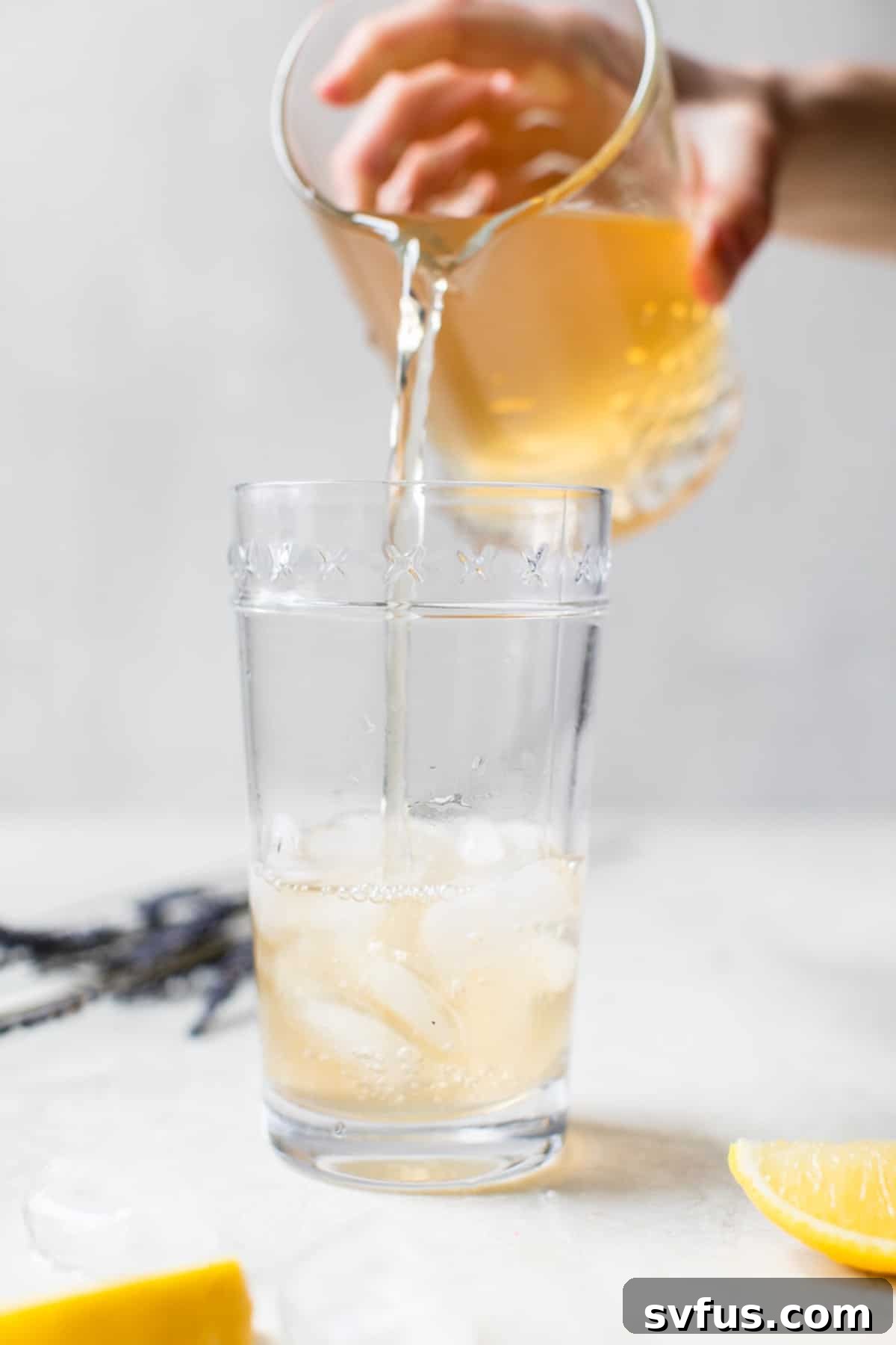 cocktail being poured into a glass filled with ice