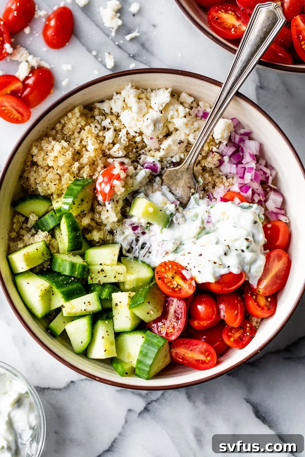 A beautifully presented Mediterranean Quinoa Bowl with a fork ready to scoop, highlighting its fresh ingredients.