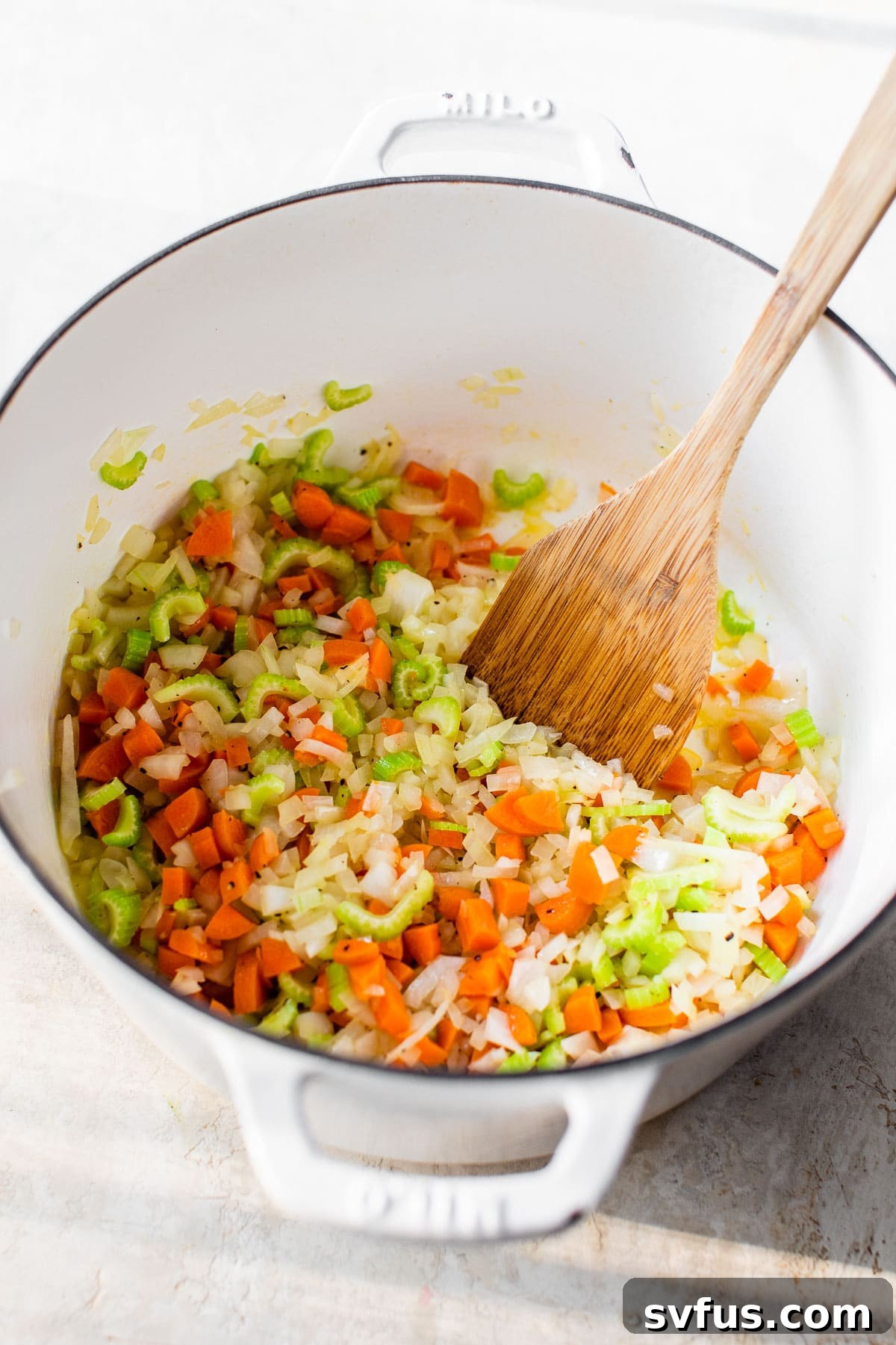 cooked onions, carrot and celery in a dutch oven, ready for next ingredients