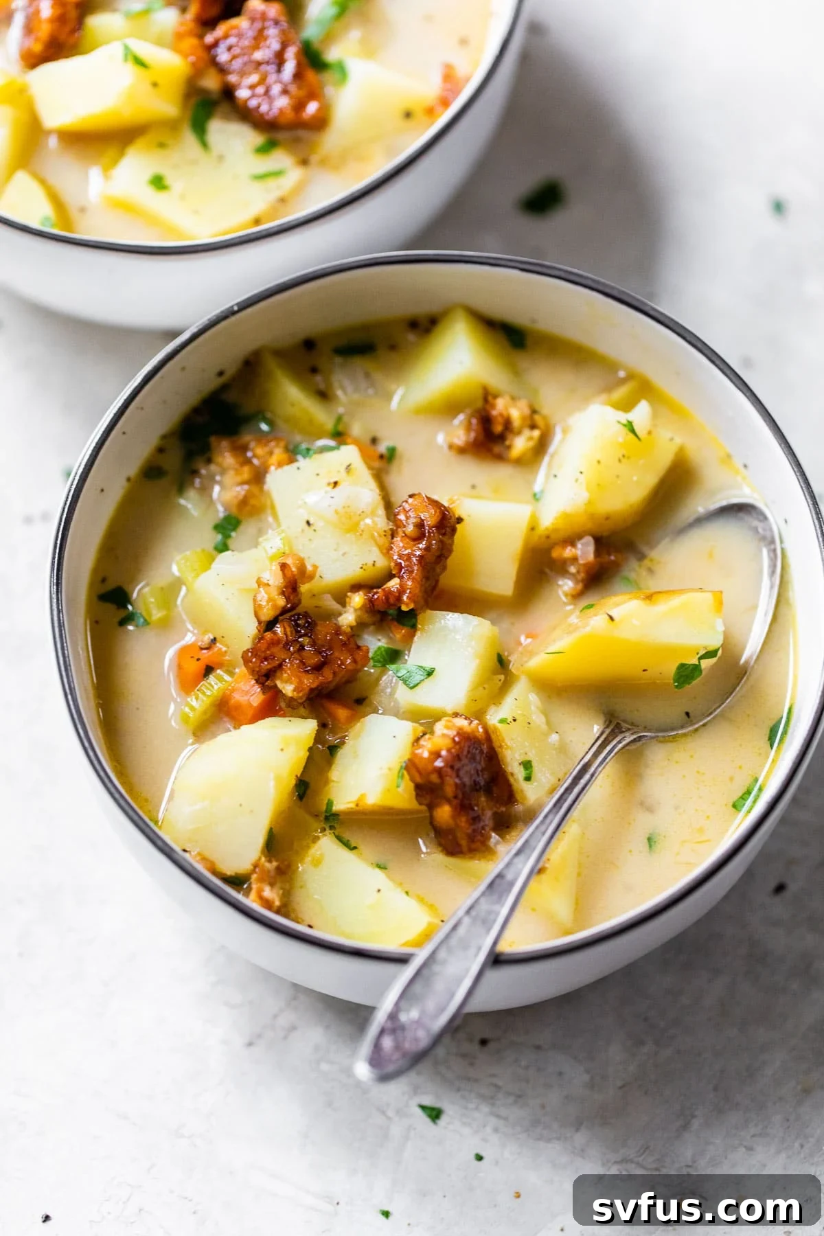 bowl of potato soup topped with cooked tempeh and fresh chives