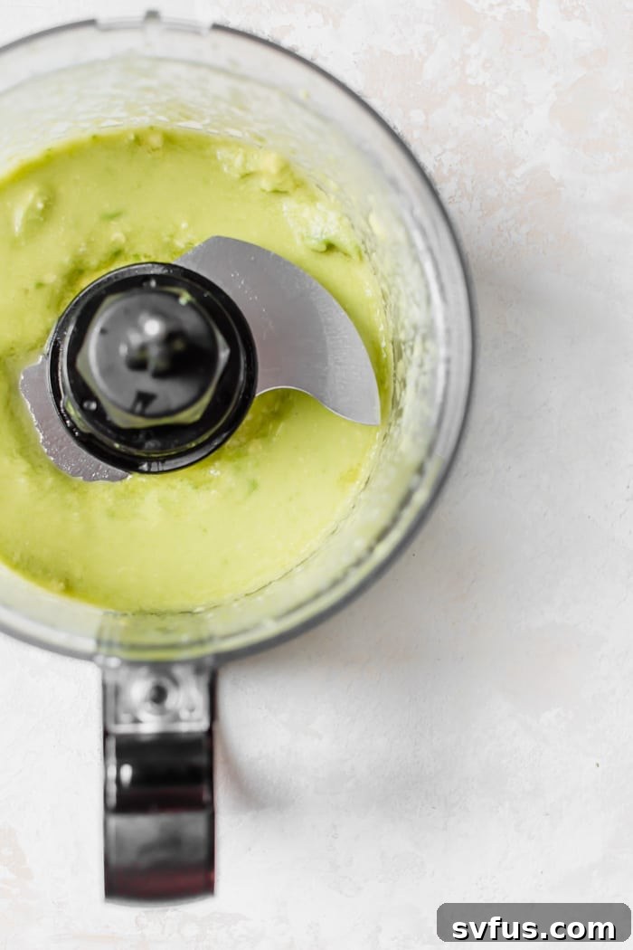 A close-up of the smooth and vibrant green avocado cream sauce in a bowl, ready to be poured.