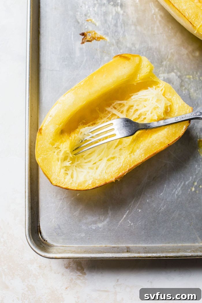 A close-up shot of a spaghetti squash half, drizzled with olive oil and placed cut-side down on a baking sheet, ready for the oven.