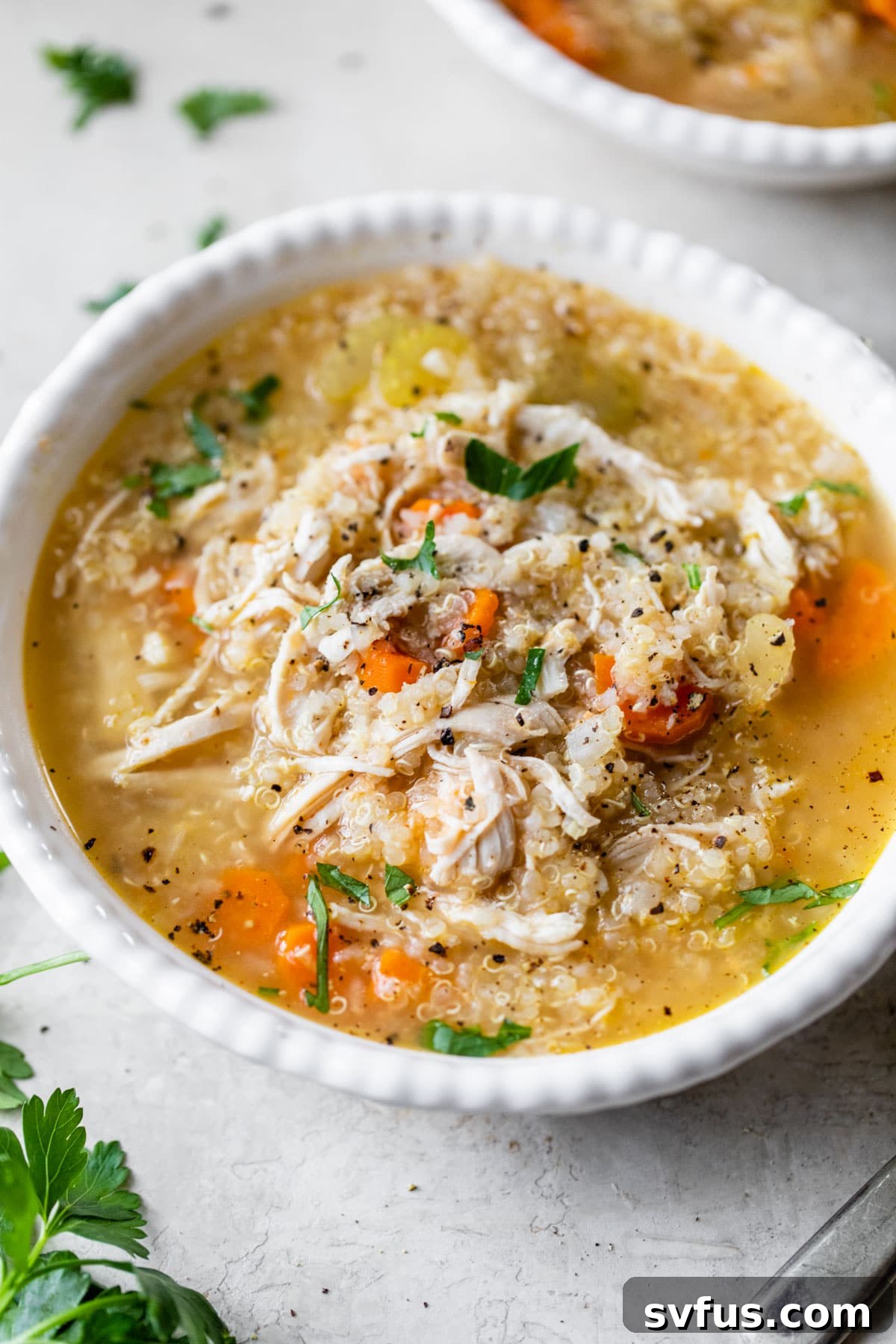 A steaming bowl of healthy Chicken Quinoa Soup garnished with fresh parsley.