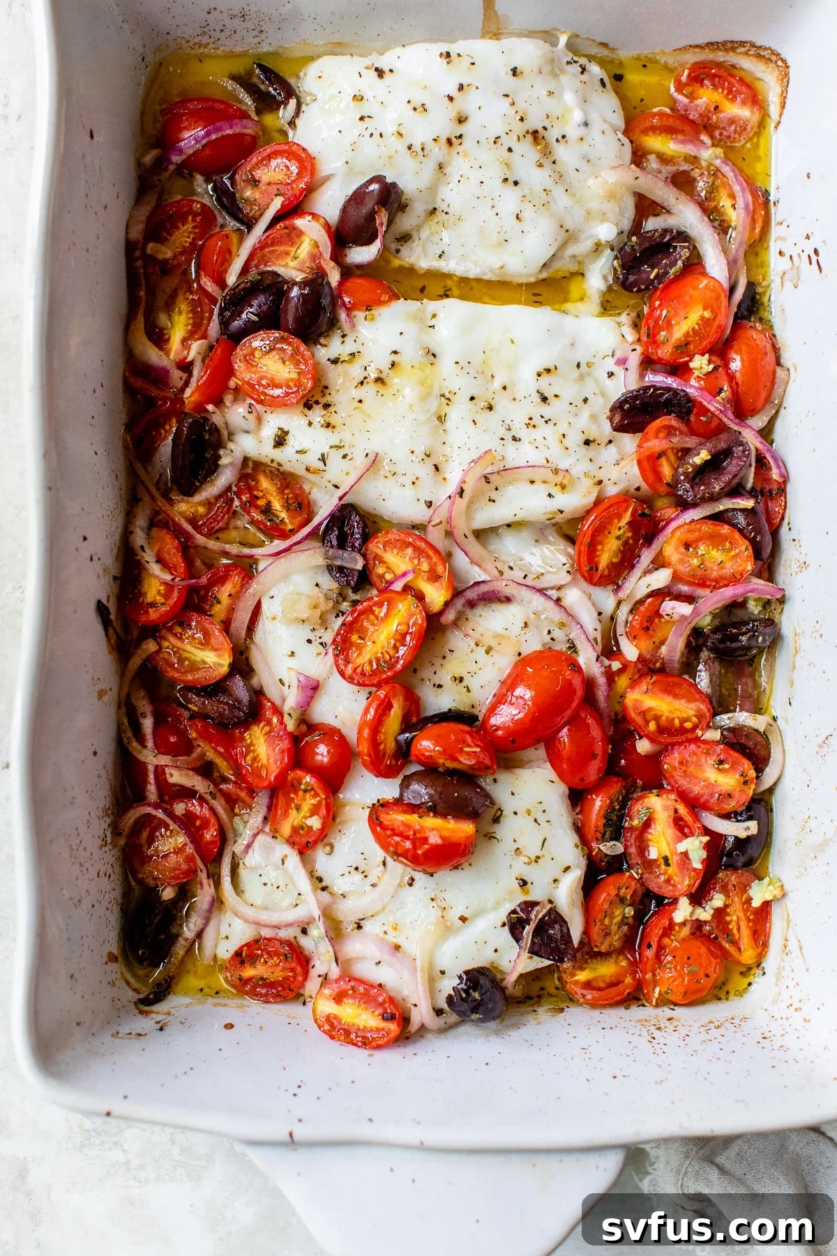 Four perfectly baked cod fillets in a baking dish, ready for serving.