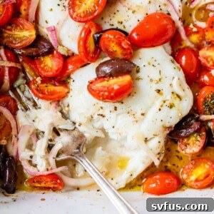 Flaky baked cod in a baking dish with tomatoes, onion and olives