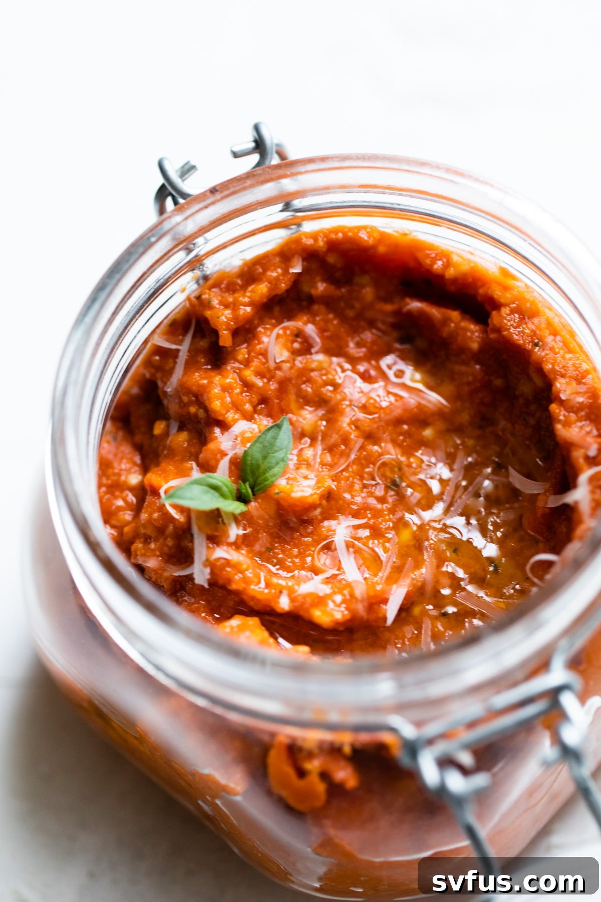 jar of sun dried tomato pesto topped with fresh basil leaves