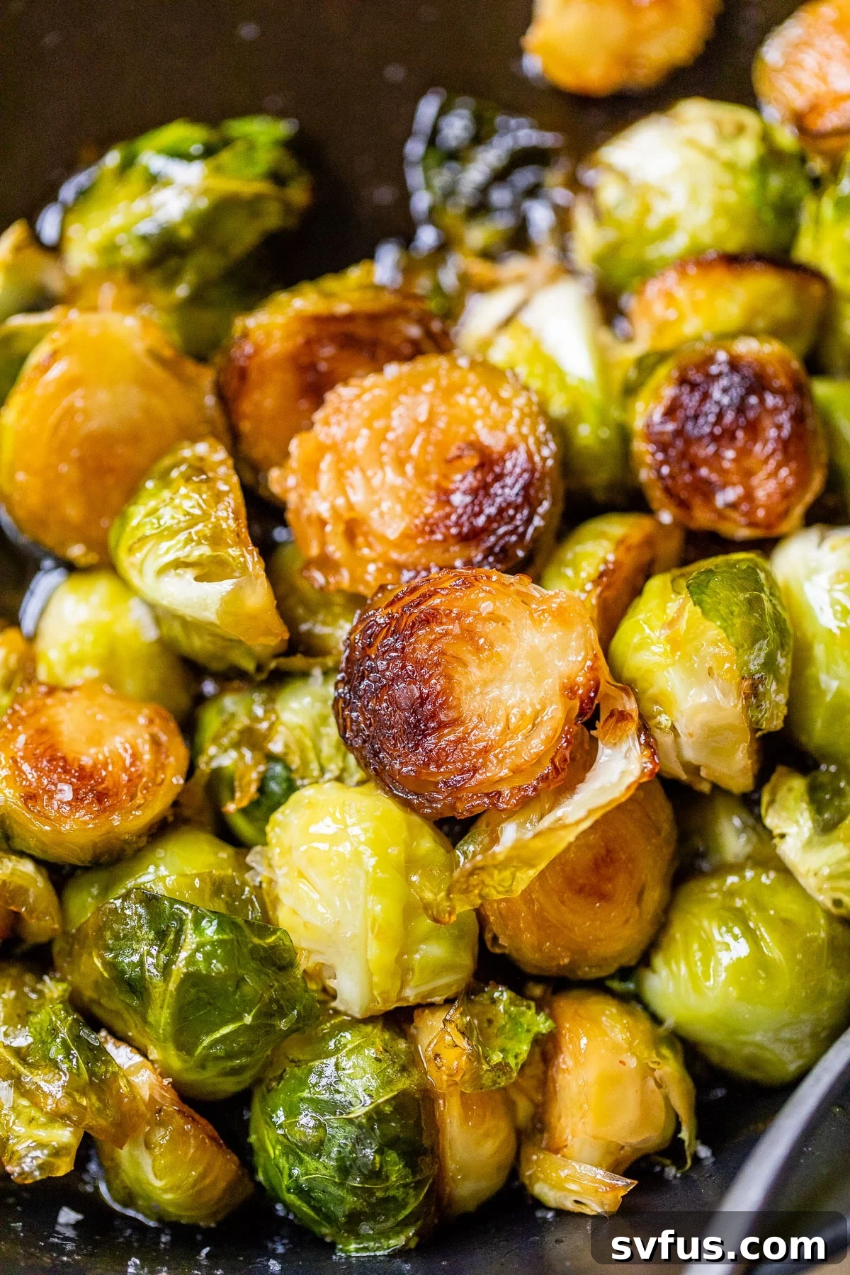 Close-up photo of perfectly fried and glazed Honey Sriracha Brussels Sprouts, showcasing their crispy edges and vibrant color.