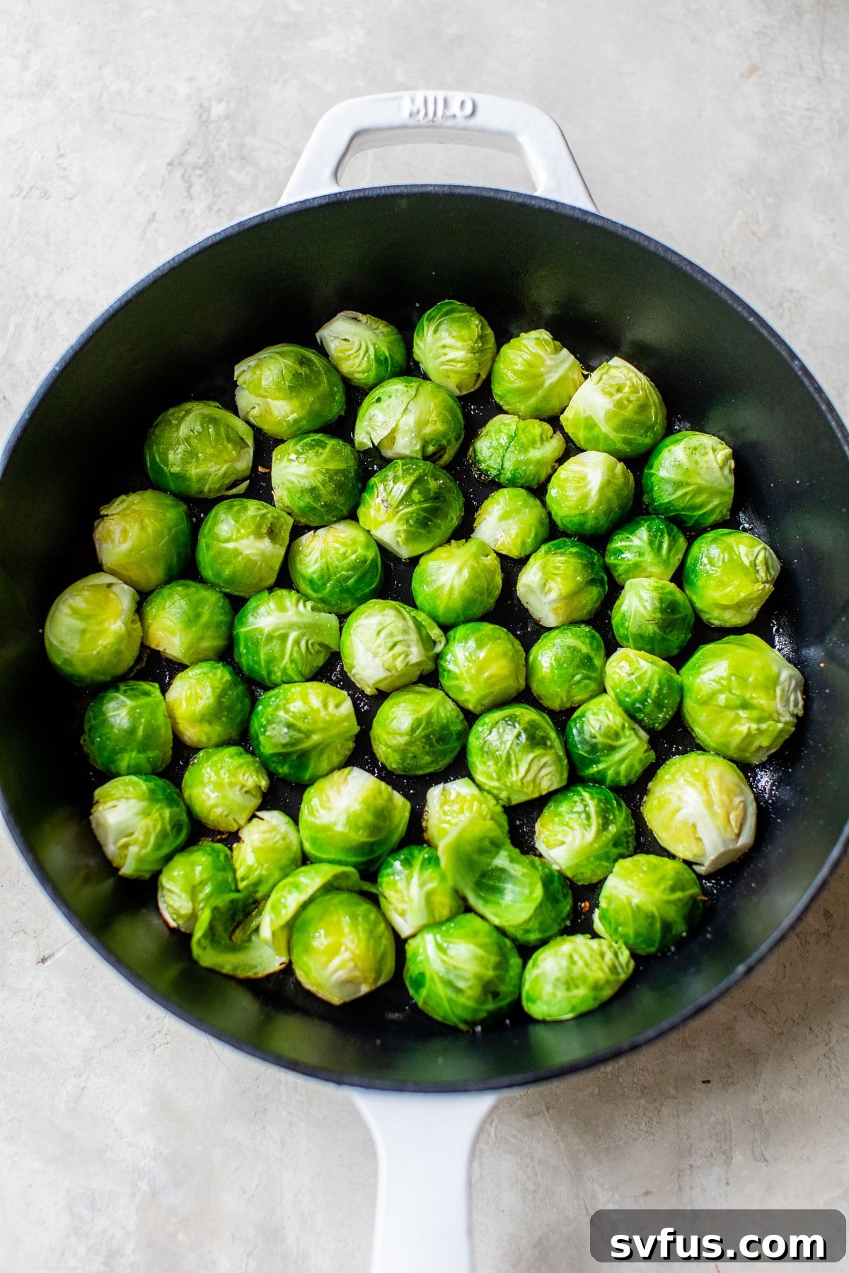 Brussels sprouts placed cut-side down in a cast iron skillet, starting to char and crisp up.