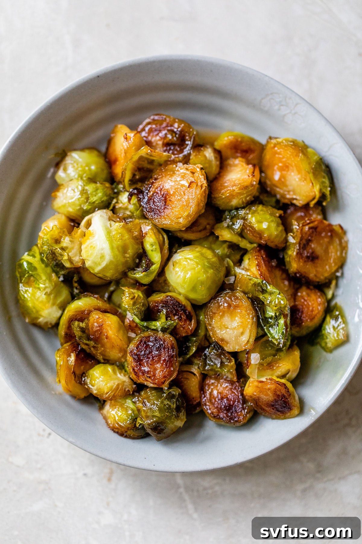 A large bowl filled with perfectly cooked Honey Sriracha Brussels Sprouts, ready for serving.