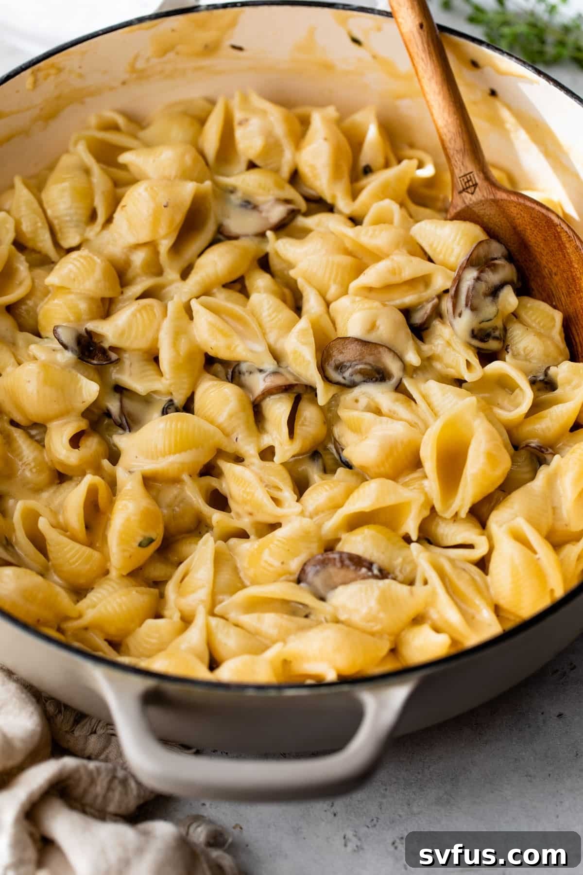 Truffle Mac and Cheese in a Dutch oven, perfectly coated in sauce, with a wooden spoon