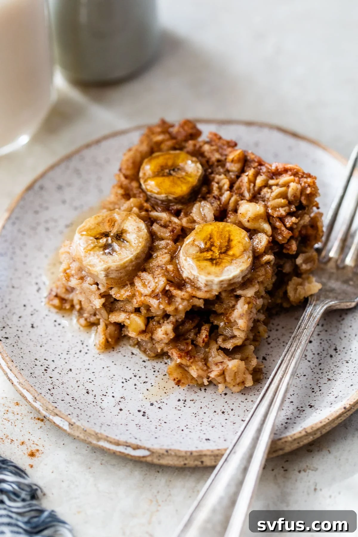 A perfectly portioned slice of baked banana oatmeal on a white plate, elegantly topped with fresh banana slices, inviting a delightful breakfast experience.