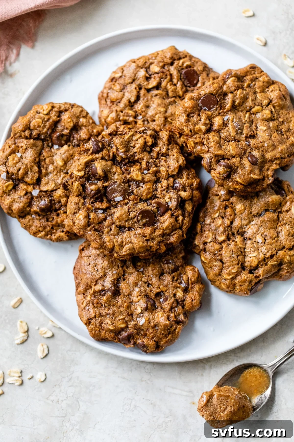 A plate piled high with golden-brown almond butter oatmeal cookies, generously studded with melted chocolate chips, ready to be enjoyed.