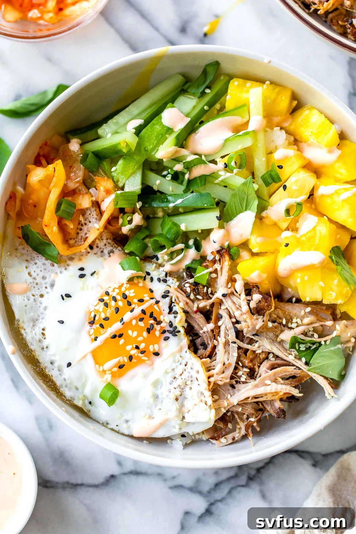 Delicious Hawaiian Bibimbap bowl topped with fresh pineapple, pulled pork, and a fried egg