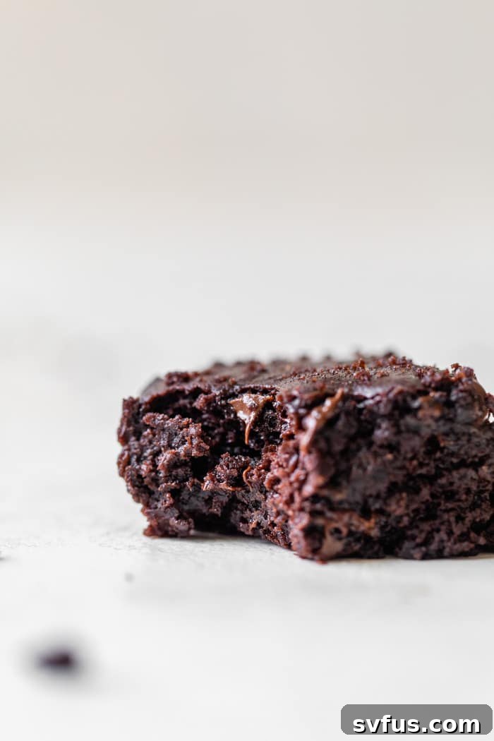 A fudgy black bean brownie with a bite taken out, showing its moist and dense texture.