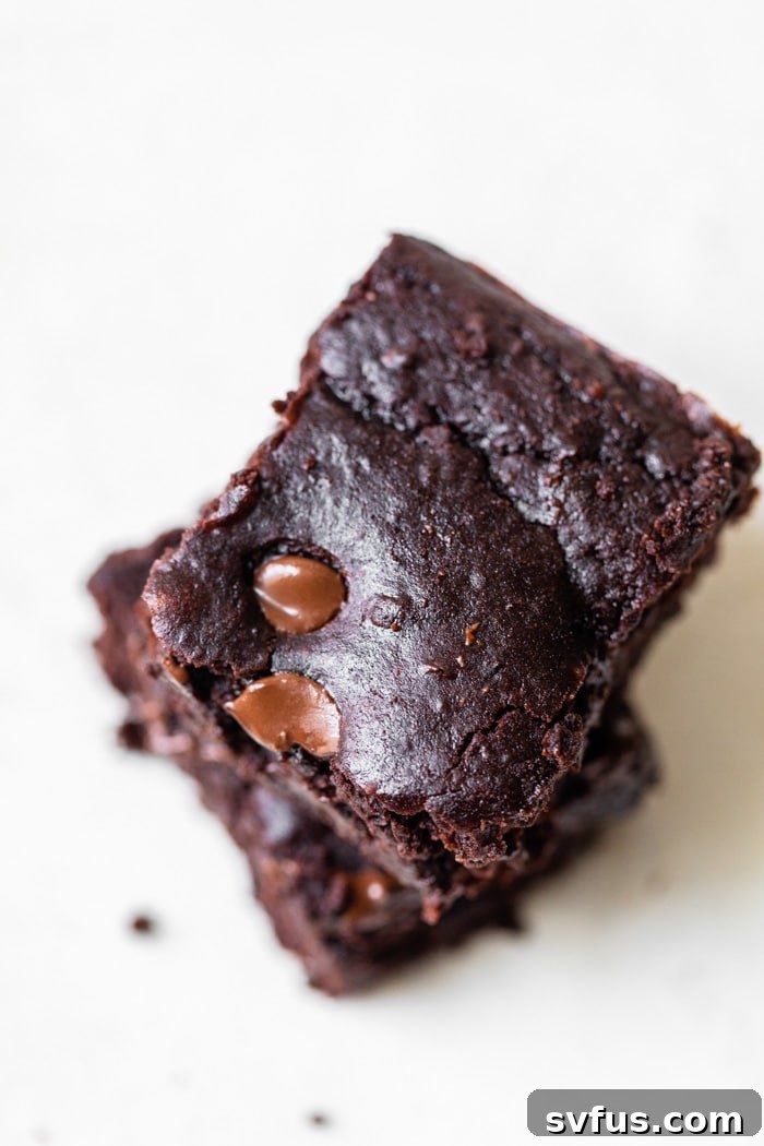 Close-up stack of freshly baked black bean brownies with visible chocolate chips, ready to eat.