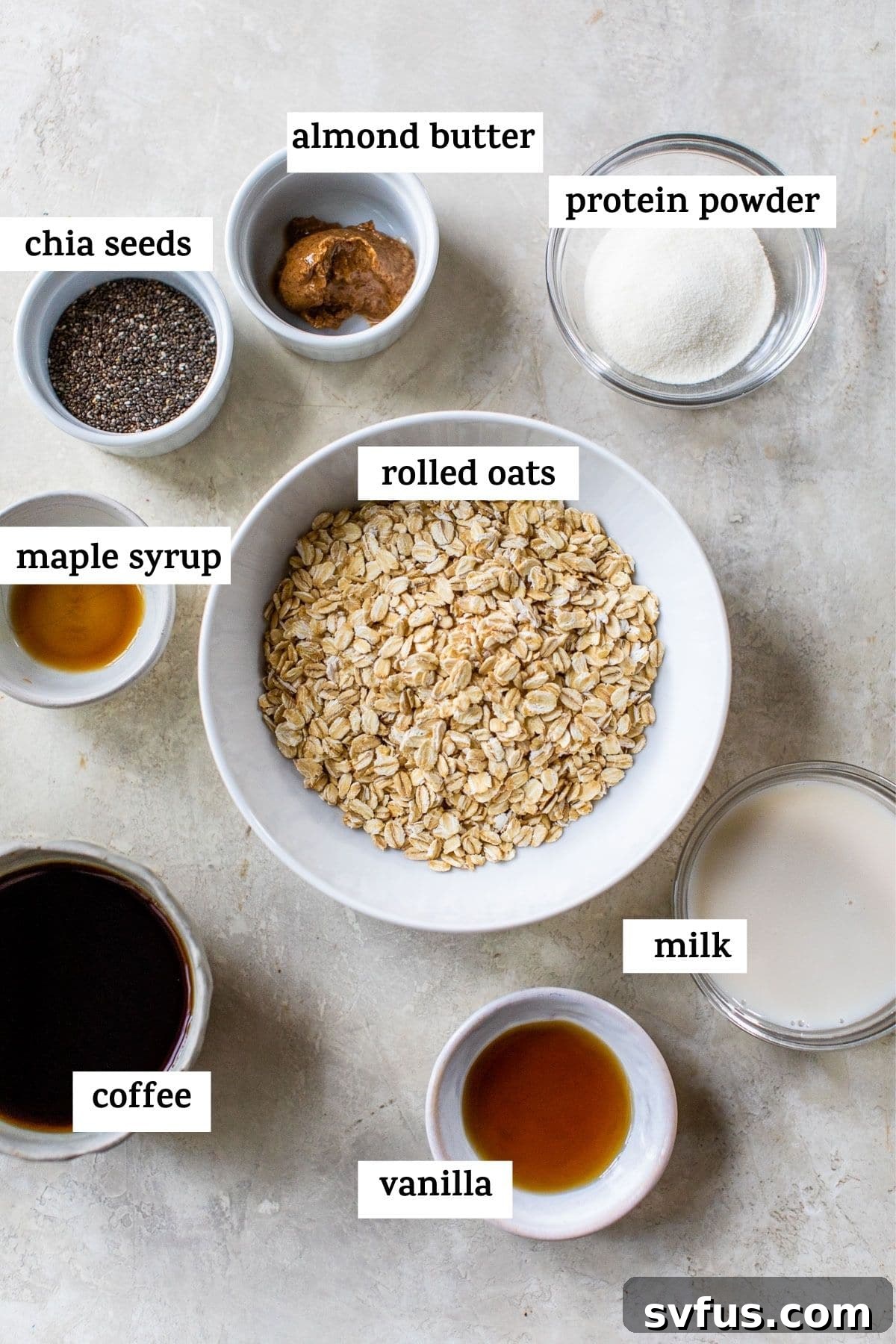 Various ingredients laid out on a white surface, including oats, coffee, milk, chia seeds, and maple syrup, ready to be combined for overnight oats.