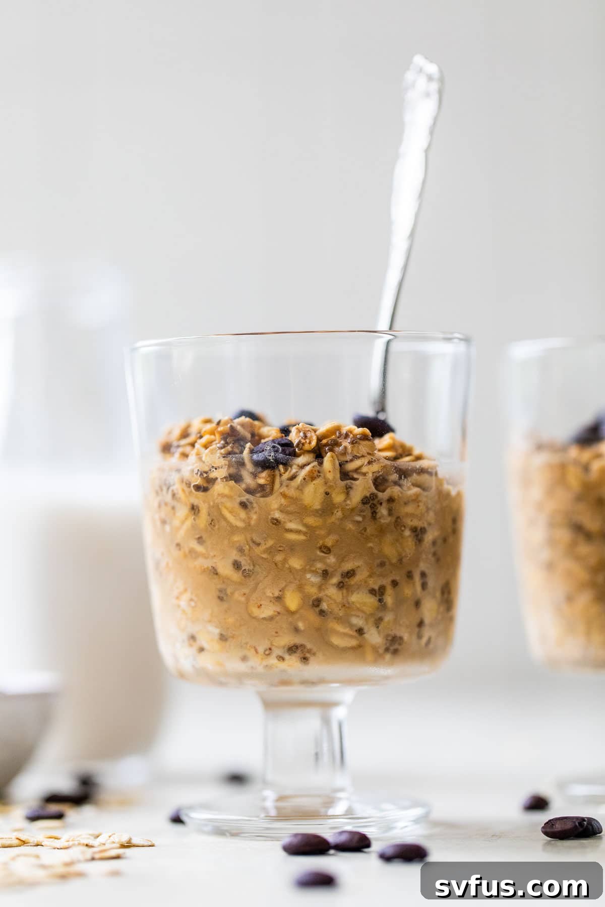 A glass jar filled with coffee overnight oats, featuring a spoon dipped inside, ready to be enjoyed as a quick breakfast.