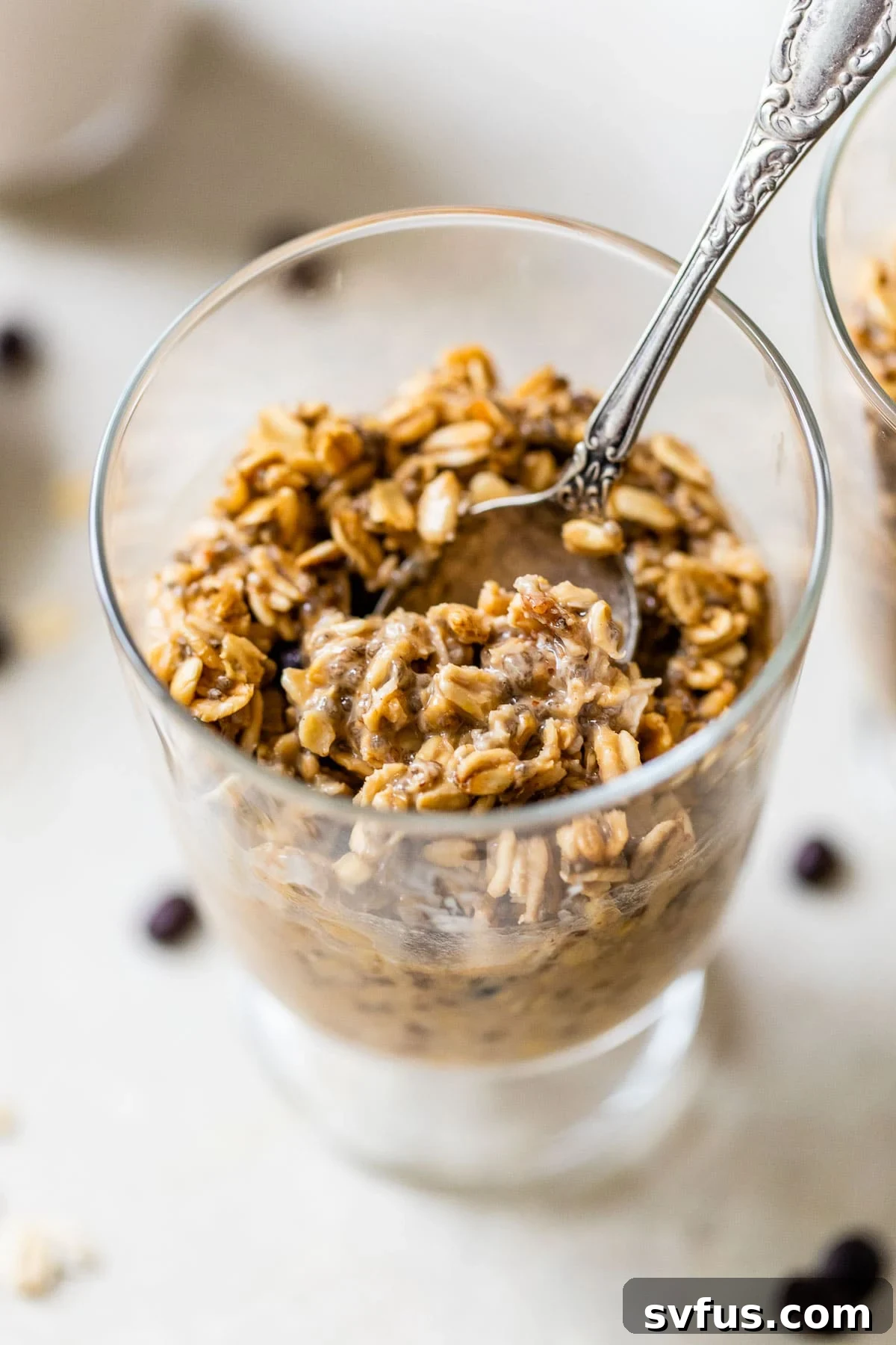A close-up shot of creamy coffee overnight oats in a glass jar, with a spoon nestled inside.
