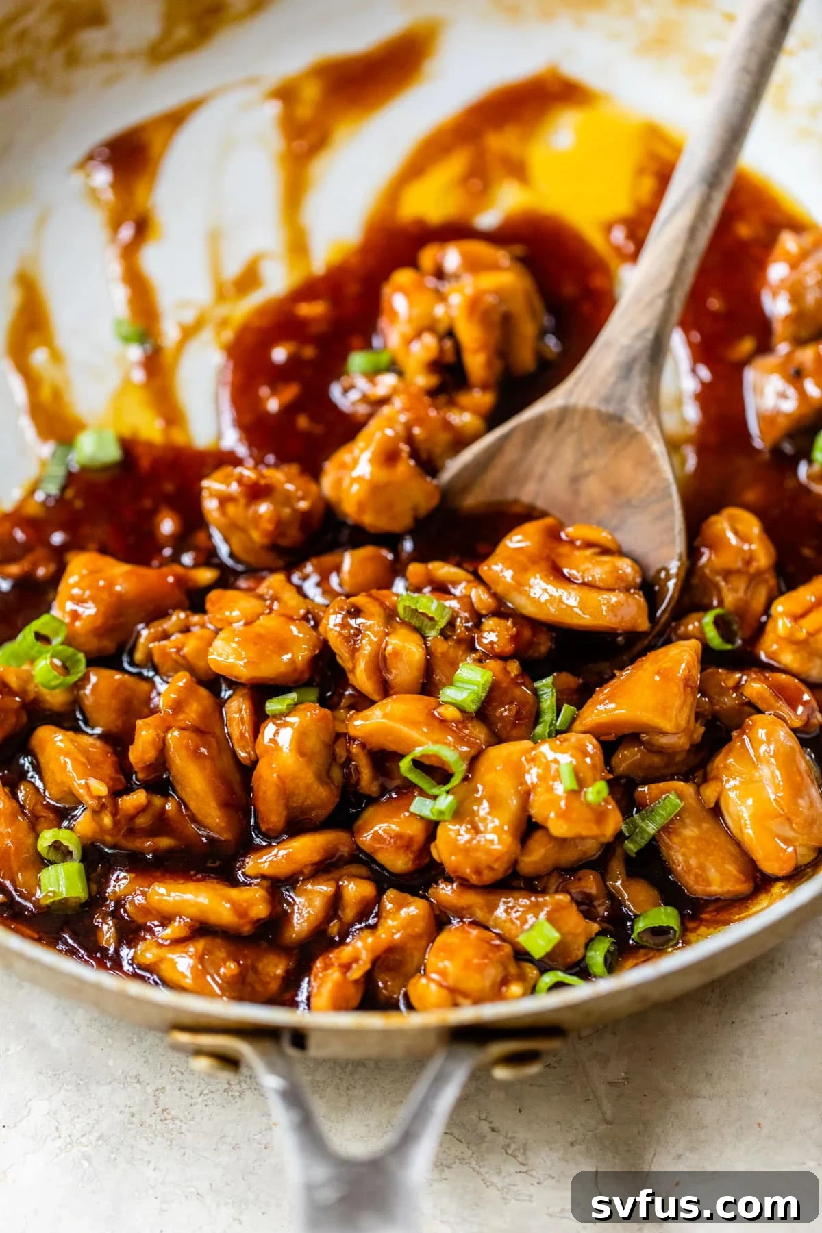 diced cooked chicken in a skillet with an Asian sauce and green onions
