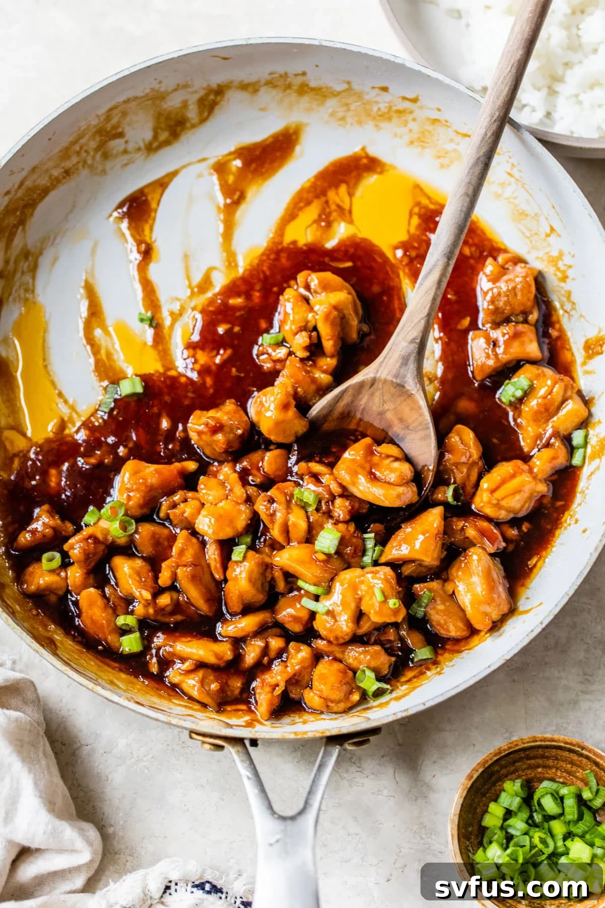 diced chicken in a skillet covered in an orange-colored sauce