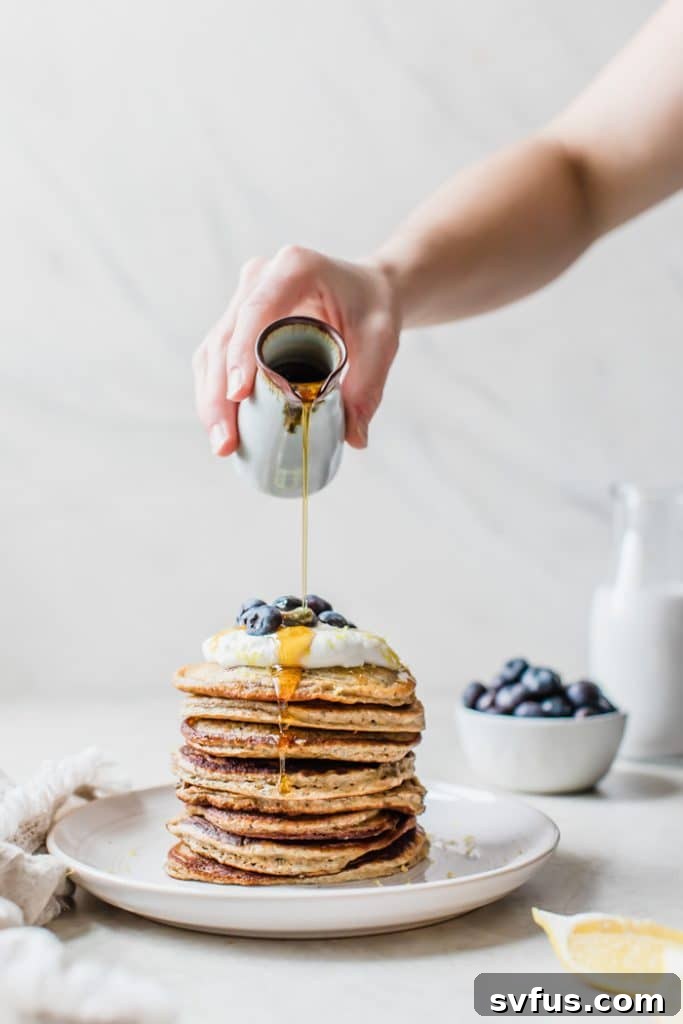 A close-up shot of a stack of blueberry chia seed pancakes with lemon yogurt and fresh blueberries, ready for breakfast