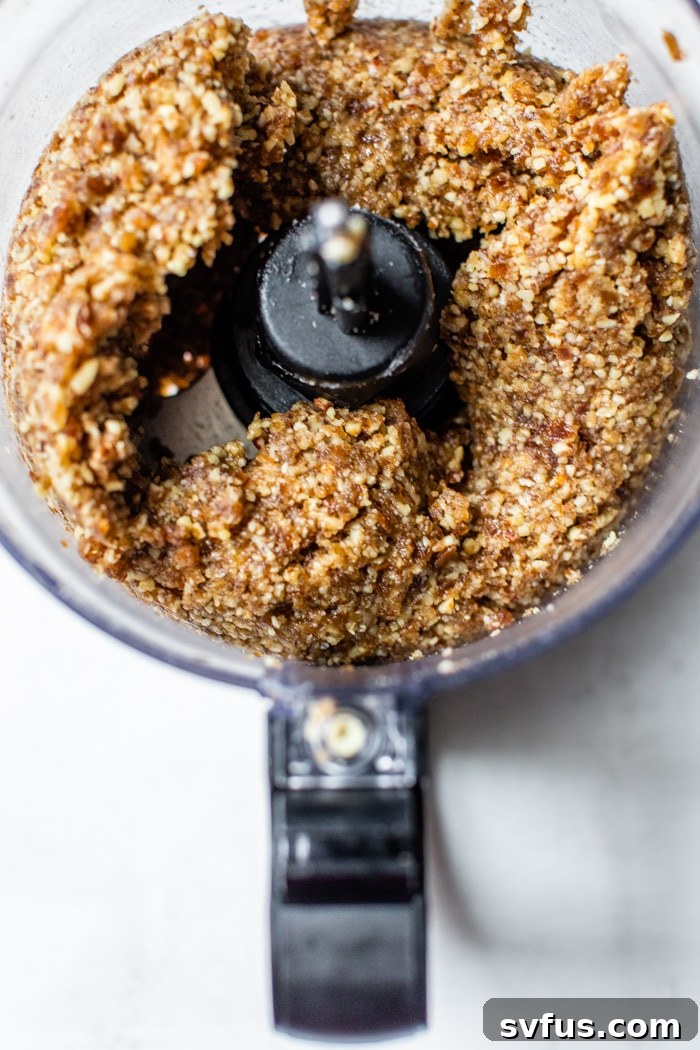 Pitted dates, walnuts, pecans, coconut oil, and maple syrup being blended in a food processor to form the tart crust mixture.