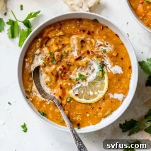 A bowl of red lentil soup topped with a lemon wedge