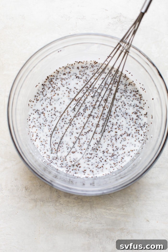 Coconut milk and maple syrup being whisked together in a glass bowl, creating a smooth liquid base for the chia pudding.