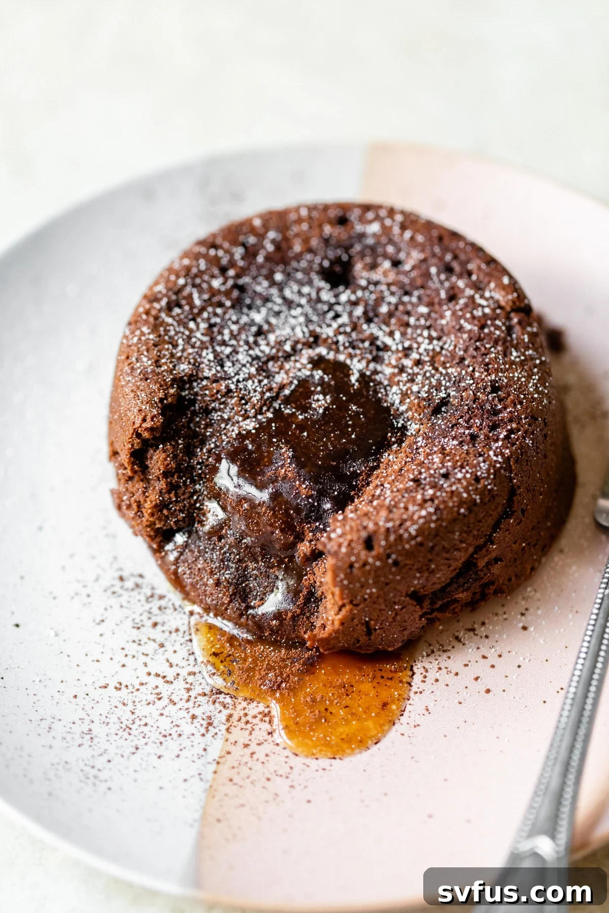 Exquisite chocolate caramel lava cake on a white plate, ready to be enjoyed with a scoop of ice cream. The cake shows a glimpse of its molten caramel center.