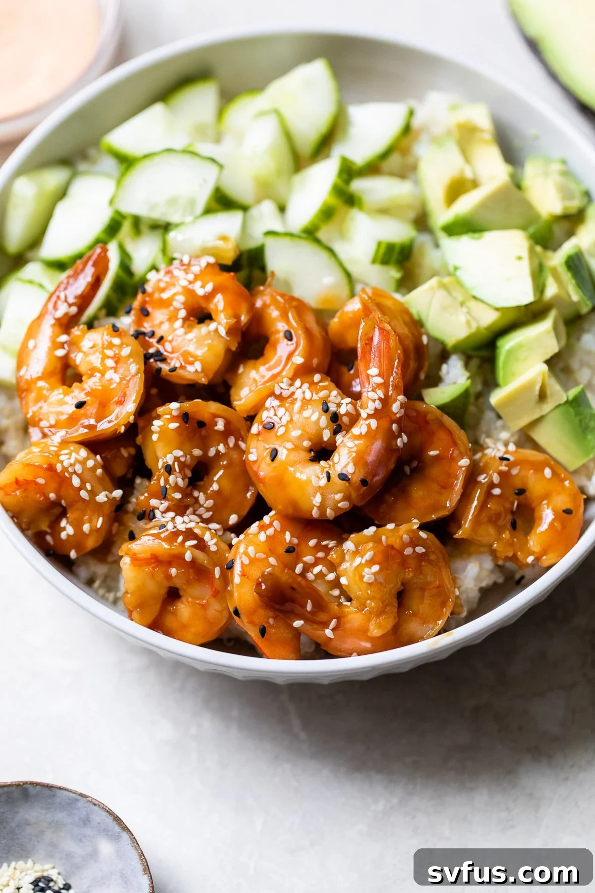 Close-up of a Teriyaki Shrimp Sushi Bowl, garnished with sesame seeds, showing the texture of the shrimp and grains.