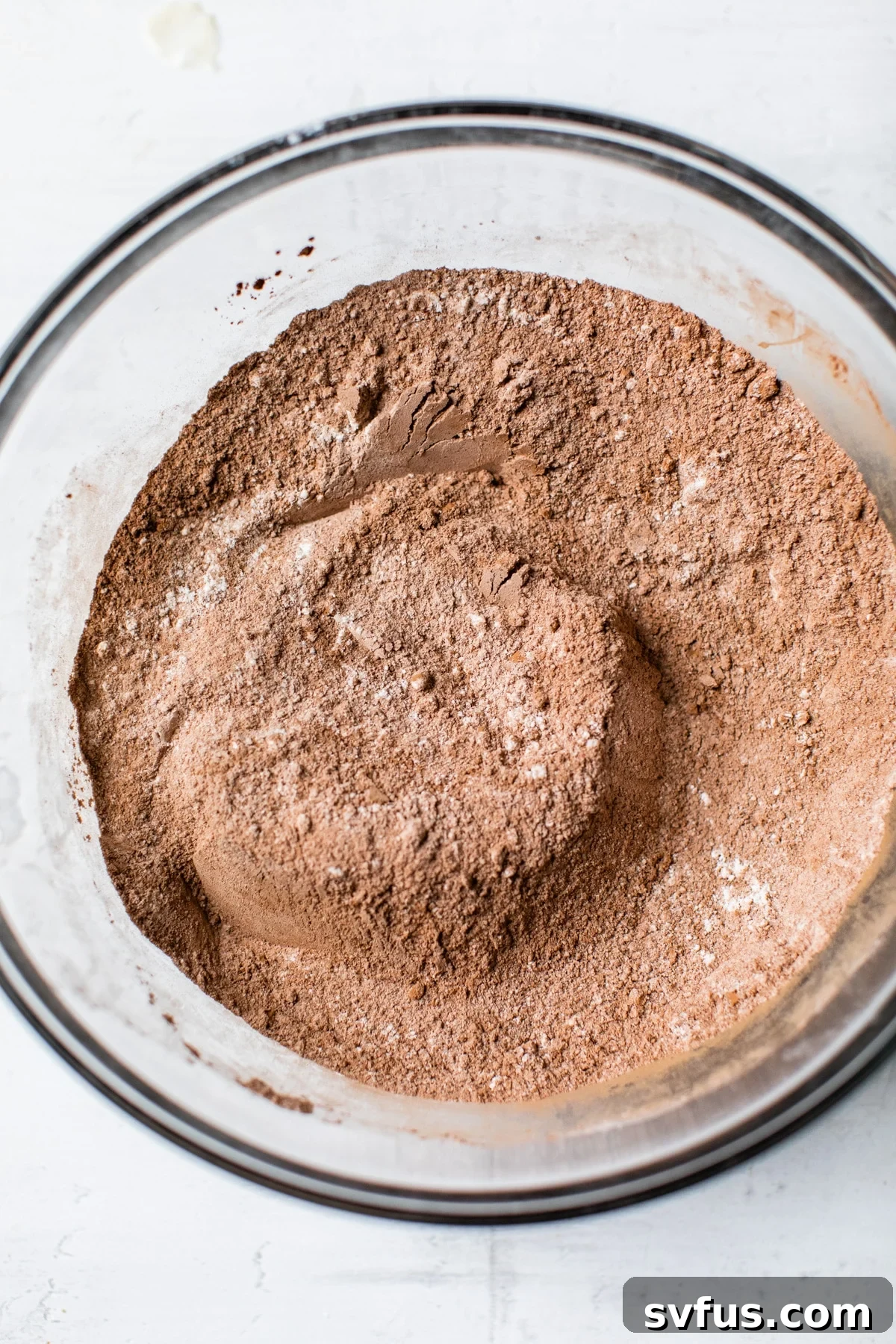 Close-up of cocoa powder and other dry ingredients in a mixing bowl.