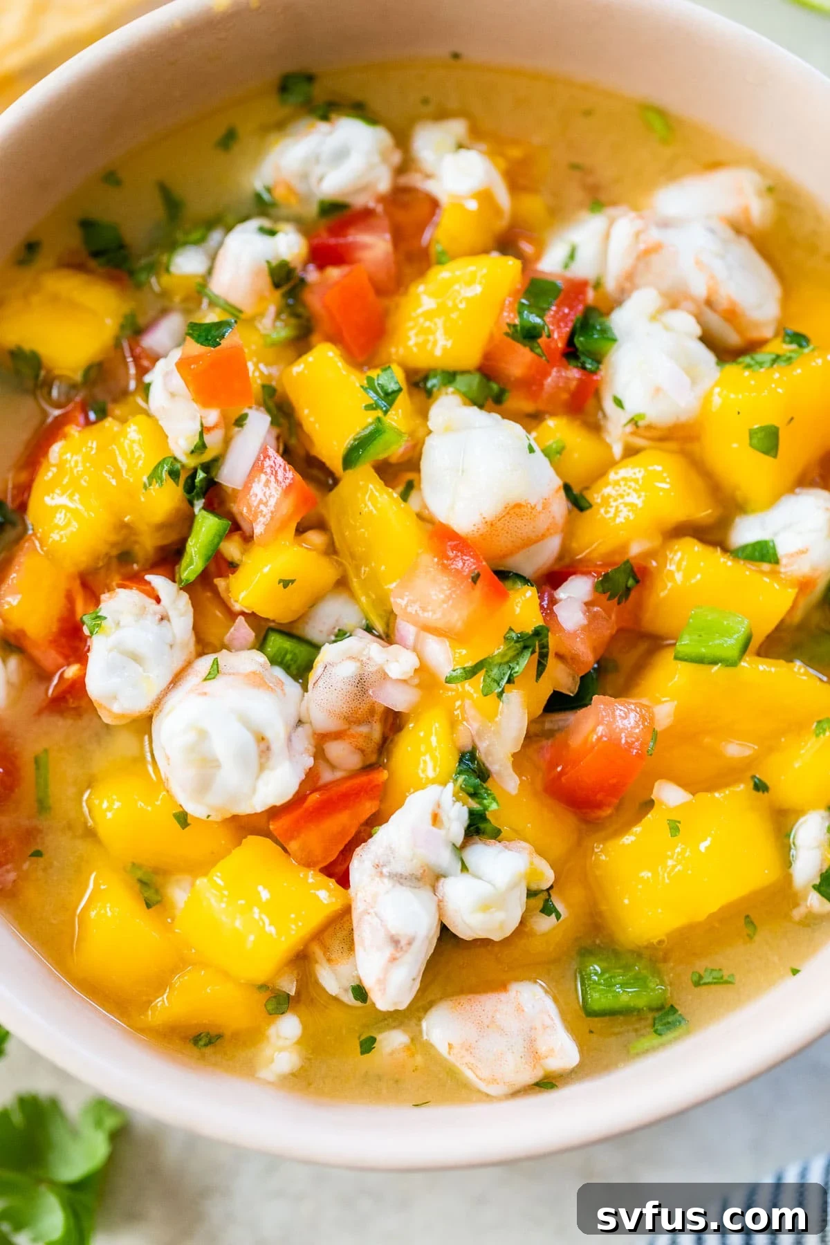 A vibrant close-up of mango shrimp ceviche in a pink bowl, highlighting the colorful ingredients and fresh appeal, ready to be enjoyed.