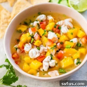 pink bowl with mango, shrimp and tomato beside a pile of tortilla chips